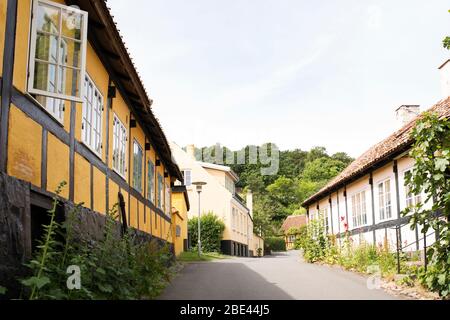 Le tradizionali case danesi costeggiano una strada in una giornata estiva a Gudhjem, sull'isola di Bornholm in Danimarca. Foto Stock