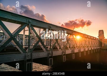 L'iconico Hungerford e il Golden Jubilee Bridge sotto il vibrante tramonto sul Tamigi vicino a Southbank, Londra, Regno Unito Foto Stock