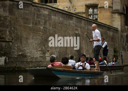 I cacciatori guidano i gruppi turistici lungo il fiume Cam a Cambridge, Inghilterra, Regno Unito, passando davanti agli edifici storici del college. Foto Stock