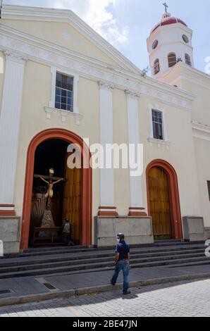 Un uomo prega davanti a un'immagine di Gesù Cristo crocifisso in una chiesa di Caracas in una settimana Santa atipica a causa della quarantena del Covide-19 Foto Stock