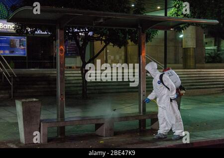 Il personale addetto alla pulizia a piedi disinfetta una piazza e strade. Giorno della notte pulizia e disinfezione nelle strade di Caracas, Venezuela, per prevenire il spr Foto Stock