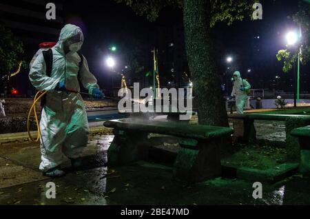 Il personale addetto alla pulizia a piedi disinfetta una piazza e strade. Giorno della notte pulizia e disinfezione nelle strade di Caracas, Venezuela, per prevenire il spr Foto Stock