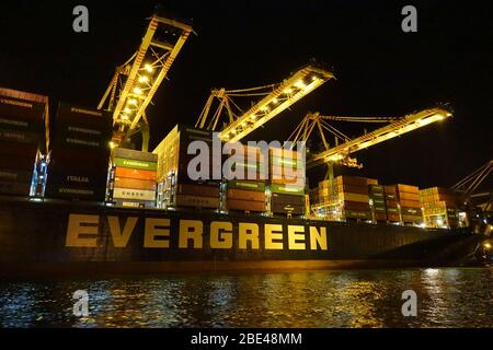 KAOHSIUNG, Taiwan -- Giugno 2, 2019: contenitori vengono caricati sulle navi nel porto di Kaohsiung all'imbrunire Foto Stock