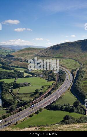 Virgin Trains classe 390 Alstom Pendolino lungo l'autostrada M6 sulla linea principale della costa occidentale nella Gola di Lune, Cumbria Foto Stock