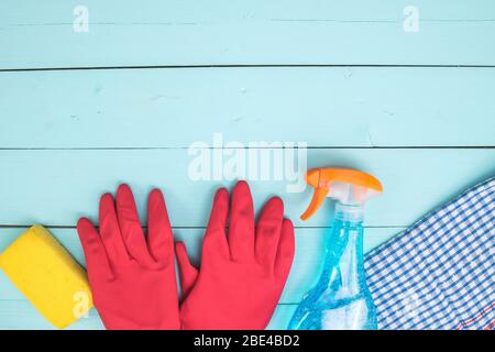 Spray detergente, guanti rosa e spugna gialla su fondo blu. Foto Stock