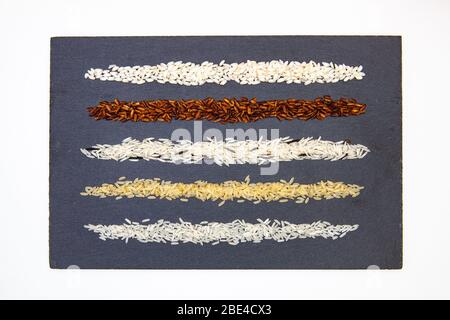 Raccolta del riso su piatto di ardesia. Diversi tipi di riso sulla scrivania di ardesia. Foto Stock