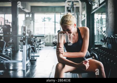 Donna hanno infortuni e male alle braccia mentre allenamento e peso in palestra, il concetto di dolore muscolare Foto Stock