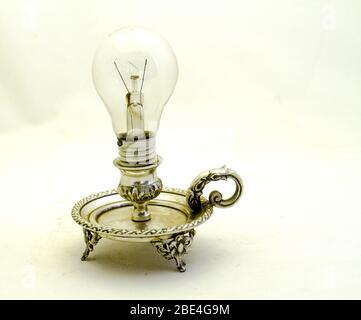 Lampadina elettrica in un portalampada vintage argento isolato su un'immagine di sfondo chiaro con spazio di copia in formato orizzontale Foto Stock