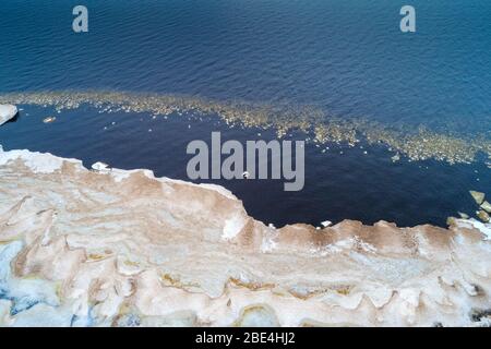 Vista dall'alto della neve che si scioglie sulla riva del lago Ladoga in un giorno di marzo (fotografia aerea). Regione di Leningrado, Russia Foto Stock