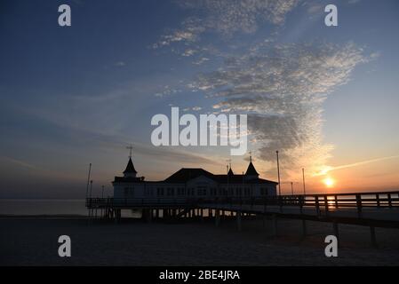 Ahlbeck, Germania. 12 aprile 2020. Le nuvole si muovono nelle prime ore del mattino durante l'alba nel cielo sopra il molo sull'isola di Usedom. Il molo lungo 280 m è stato aperto nel 1898 ed è il più antico della Germania. Credit: Stefan Sauer/dpa/Alamy Live News Foto Stock