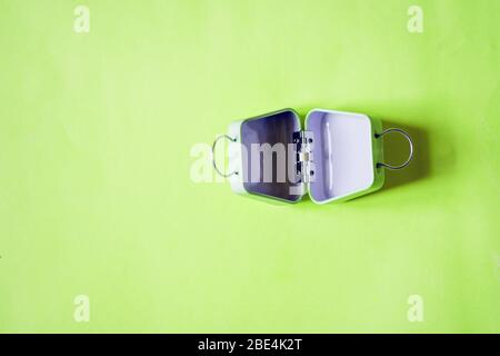 Valigia vuota in miniatura isolata su sfondo verde con spazio per le copie. Preparazione del viaggio, vacanza, turismo, bagagli, concetto di imballaggio bagagli. T Foto Stock