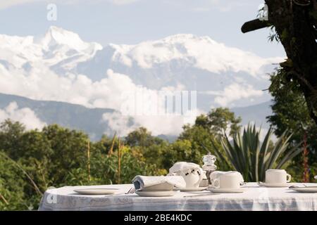 Tavolo colazione in una terrazza panoramica, con la catena montuosa Annapurna nell'Himalaya, in una località di lusso a Pokhara, Nepal Foto Stock