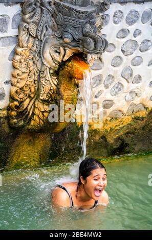 Ritratto verticale di una donna sotto le sorgenti termali di Banjar Hot Springs a Bali, Indonesia. Foto Stock