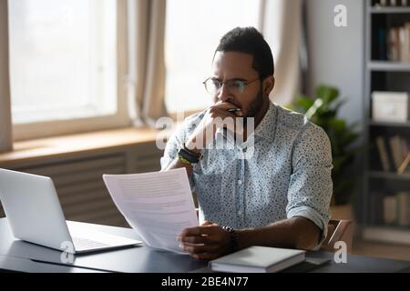 Dipendente contabile afroamericano che rivede il rapporto di ricerca. Foto Stock