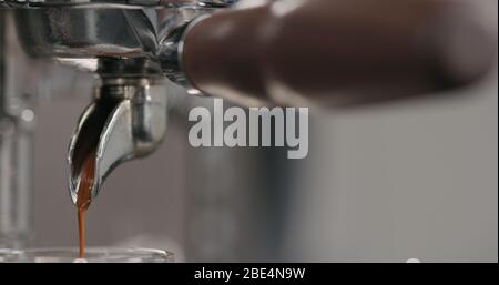 estrazione della shot di espresso con portafiltro a beccuccio singolo dalla macchina da caffè primo piano Foto Stock