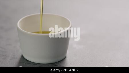 versare l'olio d'oliva nel piccolo recipiente bianco Foto Stock