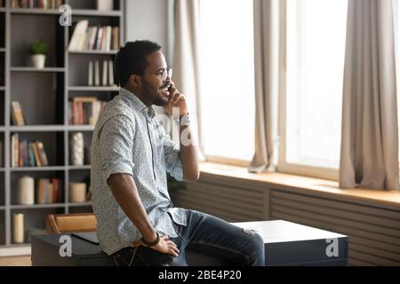 Sorridente giovane uomo d'affari americano africano che parla sullo smartphone. Foto Stock