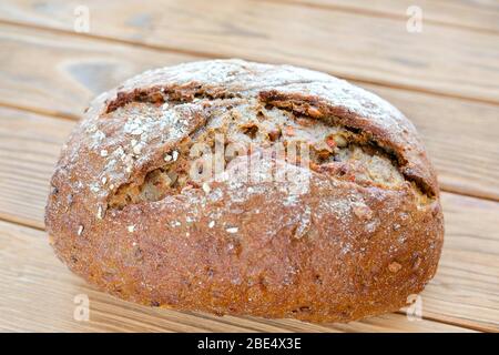 Pane di carota su sfondo di legno. Pezzo di pane non tagliato. Prodotto realizzato in casa e rispettoso dell'ambiente. Foto Stock