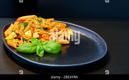 Pasta italiana: Penne rigate senza glutine, con farina di lenticchie, zucchine, pomodori ciliegini, basilico e semi di basilico Foto Stock