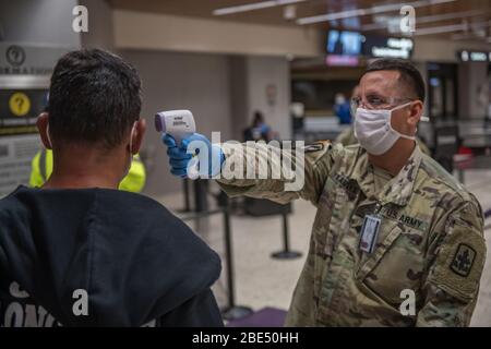 HONOLULU, USA - 06 aprile 2020 - SPC. James Kamaka, 1° Squadron, 299° Cavalleria, Hawaii National Guard (HING) schermi in partenza passeggeri presso il Danie Foto Stock