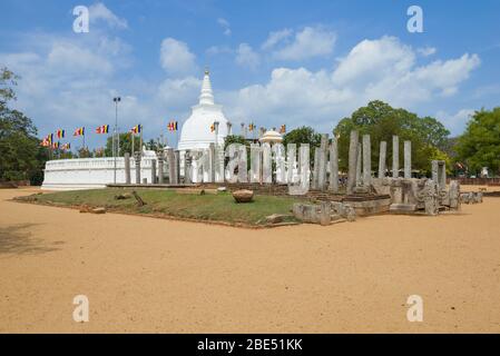 Rovine di un antico tempio buddista sullo sfondo di Thuparama Dagoba in una giornata di sole. Anuradhapura, Sri Lanka Foto Stock