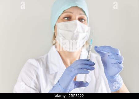 Il medico nella maschera contiene una siringa con un vaccino contro il virus Foto Stock