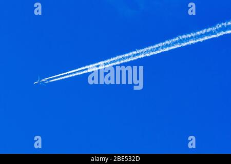 Una linea di jet doppia con motore Delta Airlines lascia un sentiero di vapore contro un cielo blu. Foto Stock