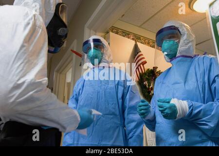 LITTLETON, USA - 03 aprile 2020 – i soldati rimuovono le maschere facciali con candeggina e acqua e rimuovono i guanti in lattice dopo aver somministrato un COVID-19 Foto Stock