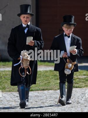 Rosenthal, Germania. 12 aprile 2020. Due ragazzi giocano a Pasqua nella loro fattoria con un cavallo di legno. Tradizionalmente i cavalieri pasquali sono in sella alla domenica di Pasqua nelle zone cattoliche dell'alta Lusazia da oltre 500 anni. A causa della pandemia di Corona, quest'anno non si svolgerà il pasquale. Credit: Robert Michael/dpa-Zentralbild/dpa/Alamy Live News Foto Stock