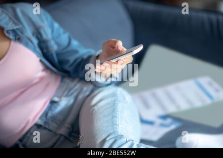 Donna seduta sul divano, con telecomando Foto Stock