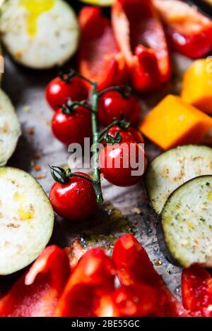 Cena Detox salutare con verdure diverse, come melanzane, pepe rosso, pomodori ciliegini, zucca alle butternut. Fette di verdure crude preparate per la torrefazione, semplice pasto di famiglia Foto Stock