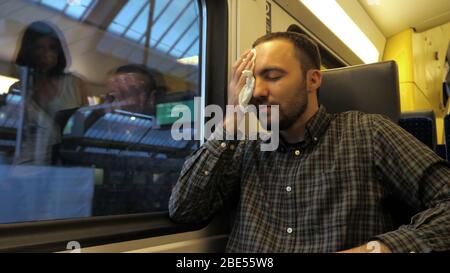 Uomo maturo tosse in treno. Foto Stock