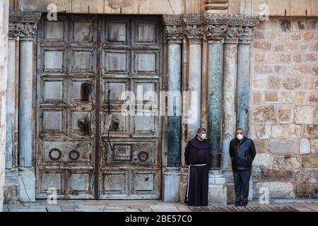 Gerusalemme, Israele. 12 aprile 2020. Un clergyman cristiano e un uomo si trovano davanti alla Chiesa del Santo Sepolcro prima dell'inizio del servizio della domenica di Pasqua, in mezzo all'epidemia di coronavirus (COVID-19). Credit: Ilia Yefimovich/dpa/Alamy Live News Foto Stock