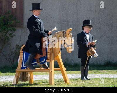 Rosenthal, Germania. 12 aprile 2020. Due ragazzi giocano a Pasqua nella loro fattoria con un cavallo di legno. Tradizionalmente i cavalieri pasquali sono in sella alla domenica di Pasqua nelle zone cattoliche dell'alta Lusazia da oltre 500 anni. A causa della pandemia di Corona, quest'anno non si svolgerà il pasquale. Credit: Robert Michael/dpa-Zentralbild/dpa/Alamy Live News Foto Stock