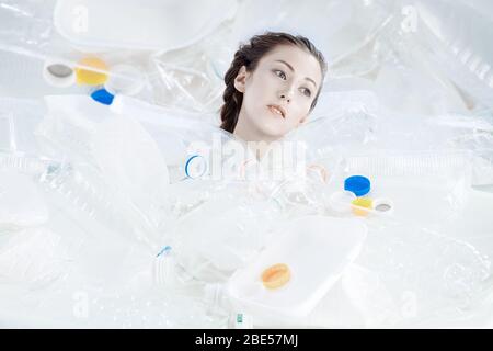 Un uomo sta annegando in un mare di plastica. La testa delle ragazze affonda tra i tipi differenti di plastica. Foto Stock