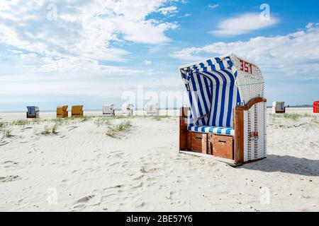 Sedia da spiaggia o panca in legno a strisce blu e bianche su una spiaggia tropicale di sabbia bianca sotto il sole estivo in un concetto di viaggio e vacanza Foto Stock