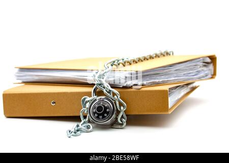 Cartelle di documenti di cartone bloccate con catena e lucchetto. Messa a fuoco selettiva con profondità di campo bassa. Foto Stock