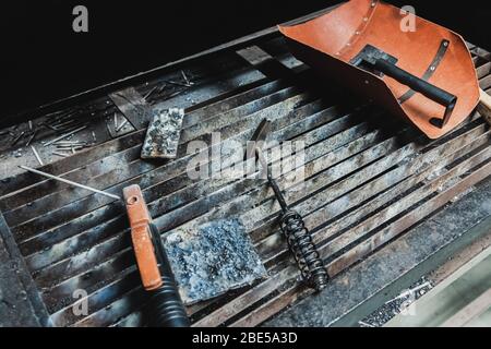 Attrezzature poste sul metallo elettrico banco di saldatura comprendente la maschera di protezione, Metal Hammer, spazzola in acciaio e la piastra in acciaio Foto Stock