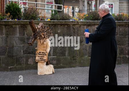 Un sacerdote si trova di fronte ad una scultura di Gesù che porta una croce durante la Pasqua in mezzo a focolaio di coronavirus in Sopot.Poland ha confermato 6,356 casi di coronavirus, 208 morti e 375 casi recuperati. Foto Stock