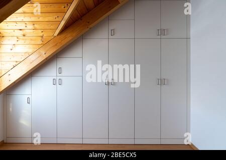 Una vista interna di un armadio su misura costruito in una camera da letto principale con un tetto spiovente Foto Stock