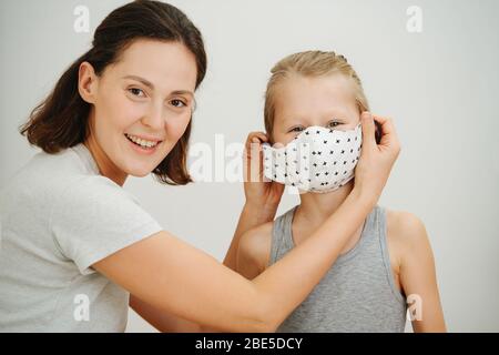 Madre e figlio, prova su una nuova maschera protettiva. Vita familiare nella chiusura Foto Stock