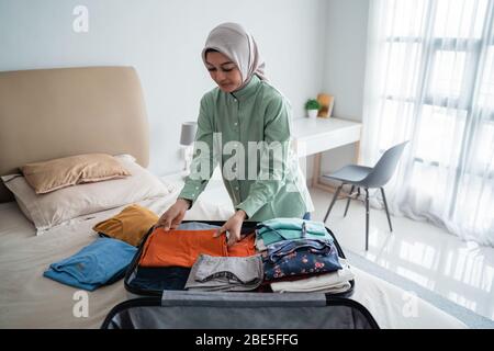 Belle donne musulmane che preparano vestiti da mettere in una valigia prima di un viaggio di vacanza Foto Stock