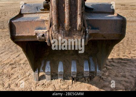 Benna di un escavatore da costruzione in un cantiere. La parte di lavoro dell'escavatore per scavare la terra. Primo piano. Foto Stock