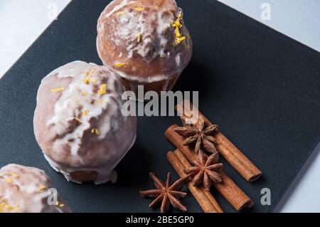 Muffin freschi con crema di annaffiatura con anice stellato e cannella su sfondo nero. Foto Stock