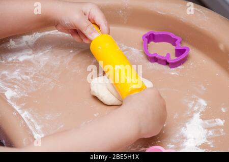 Il bambino produce la pasta fatta in casa. Pin di laminazione, pasta e farina sul tavolo. Cottura fatta in casa. Cottura dall'impasto domestico. Foto Stock