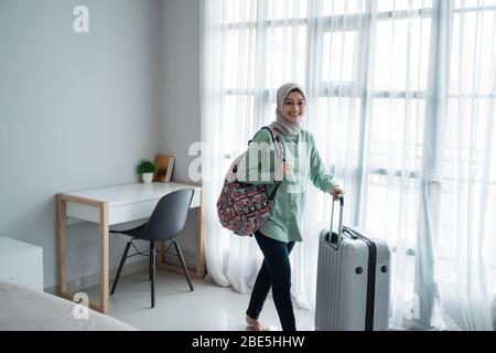 beauty giovane hijab viaggiatore camminare e portare la sua borsa e tenere la valigia nelle finestre anteriori con tenda Foto Stock