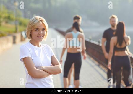 Sporty ragazza sorride sullo sfondo di amici atleti nel parco Foto Stock