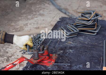 Rinforzo di piegatura della barra di rinforzo in metallo. Lavoratore che utilizza una macchina di armatura curvante per il rinforzo nei lavori di costruzione Foto Stock