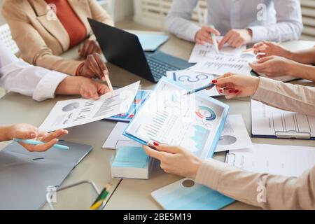 Primo piano ad angolo di inriconoscibile businesswoman che detiene il grafico dei dati con le informazioni statistiche durante la pianificazione del piano finanziario durante la riunione in ufficio, copia Foto Stock