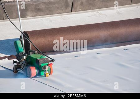 Dispositivo di costruzione per l'installazione di materiali impermeabilizzanti sul tetto. Installazione di impermeabilizzazione in un cantiere. Protezione del tetto o Foto Stock